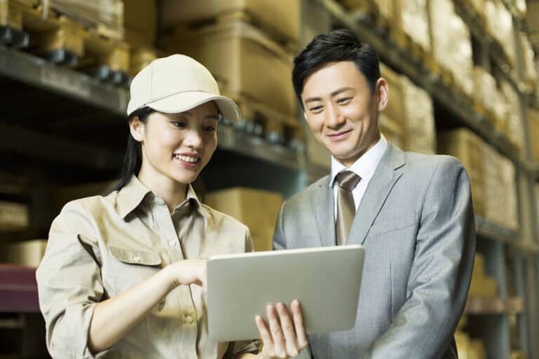 Female Chinese logistics staff showing digital tablet to businessman